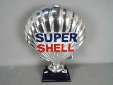 A chrome Super Shell sign on wooden base,