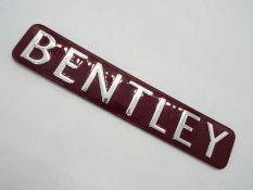 A red and chrome Bentley sign, approximately 3 cm x 17 cm.
