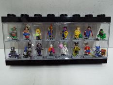 LEGO - A black plastic Lego display case in black containing 16 Lego 'Superheroes' themed