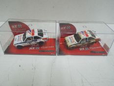 SCX Classics - 2 x Ford Escort MkII rally models in perspex display cases depicting the same