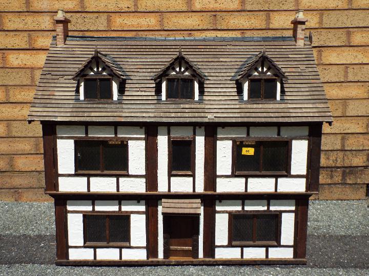 An illuminated hand built wooden three storey Tudor style dolls house,