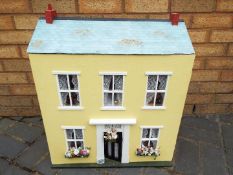 A scratch built wooden yellow two storey dolls house.