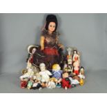 A collection of unboxed vintage and modern dolls made from a variety of materials.
