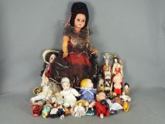 A collection of unboxed vintage and modern dolls made from a variety of materials.