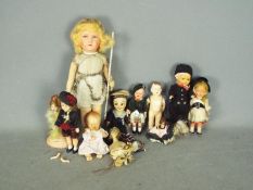 Eleven assorted vintage dolls made of various materials.