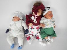Three reborn / lifelike dolls to include one by Hoomai with open brown eyes, open mouth,