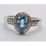 Stone Set Silver Ring Having a Centre Stone the Colour of Blue Topaz, Oval Faceted Form, Size P/Q.