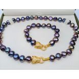 A Polynesian black pearl necklace and bracelet set with Cartier style yellow metal (untested) and