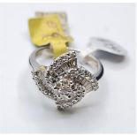 18CT WHITE GOLD FANCY TWIST FLOWER CLUSTER RING, WEIGHT 7G, 0.90CT. SIZE O