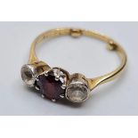 9ct gold three stone ring having a centre garnet with a white stone either side. Garnet mounted in