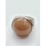 Stone set silver and moonstone ring having a large pinky brown stone set in a beaten silver shank,