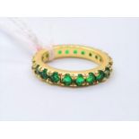 A yellow metal (untested) emerald eternity ring, size N (7.5) in a metal antique trinket box with