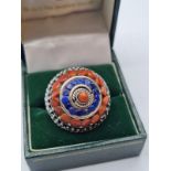 Stone set silver ring in circular form having coral colour stones with blue stones to top. Elaborate