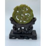 A Chinese carved green jade disc (amulet?) with a dragon and stylistic representations of clouds and