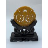 A Chinese carved yellow-orange jade disc (amulet?) with a sword and two griffins among stylised