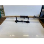 Vintage Japanese SAMURAI SWORD in snakeskin scabbard with ornate white metal hilt on display stand.