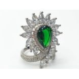 An impressive silver (stamped S925) with green and clear gems. Ring size: N. In a presentation box.