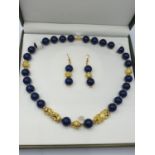 A Chinese lapis lazuli necklace with a pair of protecting lion-dogs and matching pair of earrings in