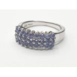 Stone set silver RING having three rows of blue topaz coloured stones to top. Clear marking for