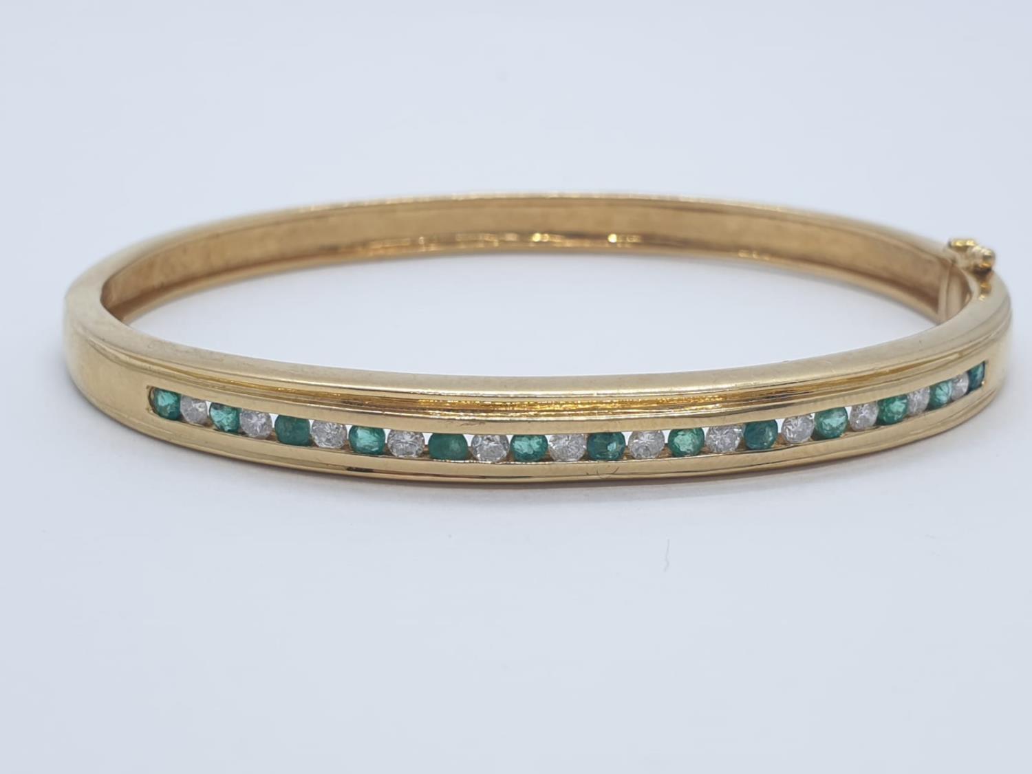 18CT Y/G DIAMOND & EMERALD BANGLE CHANNEL SET, WEIGHT 20G WITH 0.25CT DIAMONDS & 0.60CT EMERALD