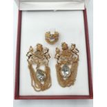 A statement pair of earrings with the British Royal Coat of Arms and a trilogy of rings with clear