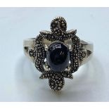 Silver RING having marcasite work to top with black onyx cabochon sit in a four claw raised mount.