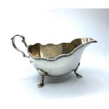 Vintage silver sauce boat standing on three cabriole legs with serpentine edge and a scroll