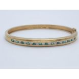 18CT Y/G DIAMOND & EMERALD BANGLE CHANNEL SET, WEIGHT 20G WITH 0.25CT DIAMONDS & 0.60CT EMERALD