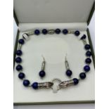 A lapis lazuli and Tibetan Style silver necklace and earrings set in a presentation box. Necklace