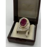 An unusual artisan?s silver (stamped 925) ring with a big faceted oval ruby central stone in its