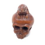 A finely carved boxwood netsuke representing a human skull with a rat Although the skull
