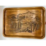 A wooden tray with relief carving of Itsukushima Shinto Shrine in Japan. It depicts the Torii (