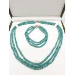 A three row of faceted Colombian Emeralds necklace and bracelet set in a presentation box.