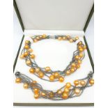 A very unusual necklace and bracelet set with large yellow-orange pearls. In a presentation box.