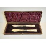 A pair of hallmarked silver butter knives with mother of pearl handles. Presented in original felt