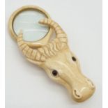 A vintage bone magnifying glass attached to a bone bull's head.