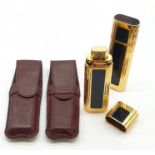 2 x Golden perfume bottles made by Cartier in a leather case. 9cm high.