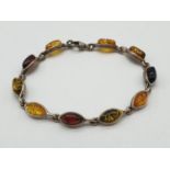 Silver and Amber bracelet, having various shades of amber stones in silver set form. 18cm approx.