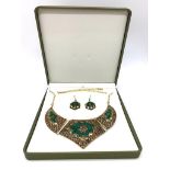 A traditional, Eastern style necklace and earrings with malachite and red coral, in a presentation