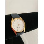 Gents Accurist slimline wristwatch. Gold tone. Genuine navy blue leather strap. Quartz movement.