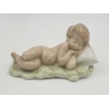 A Lladro porcelain figurine of a small child sleeping. Good condition. 10 cm long.