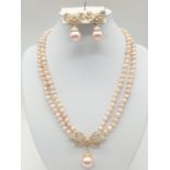 A two rows of pink pearls necklace and earrings set in a presentation box. Necklace length: 44cm,