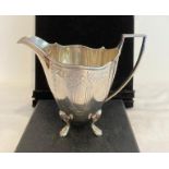 Solid silver upright milk jug, having four cabriole legs with paw feet. Attractive chased design