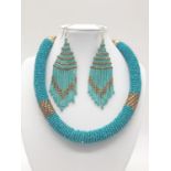 A vintage, bluish-green, North African beadwork necklace and earrings set in a presentation box.