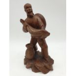 A Chinese wooden hand Carved Fisherman holding a large fish, 22cm tall