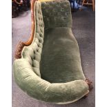 A Victorian chaise lounge with plush green velvet restoration, deep buttons and a beautiful carved