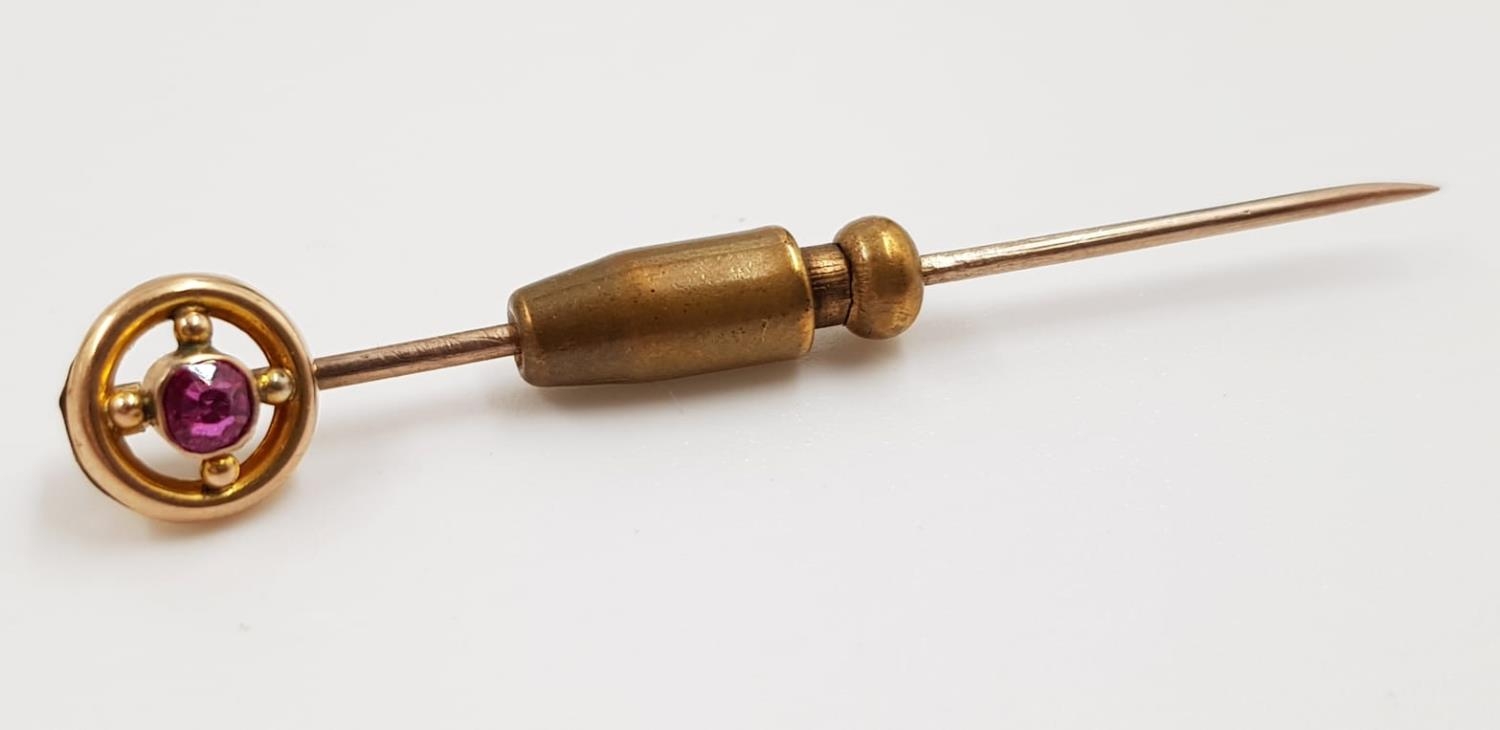 A 9ct gold stick pin; with small ruby. Weighs 2.4g and is 5cm.