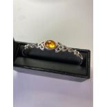 Silver BANGLE having Celtic Knot design to the top with an amber centre stone. Presented in