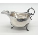 Vintage silver sauce boat having scalloped rim and scroll handle, standing on three cabriole legs