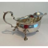 Vintage silver sauce boat having serpentine rim, scroll handle and standing on three cabriole legs